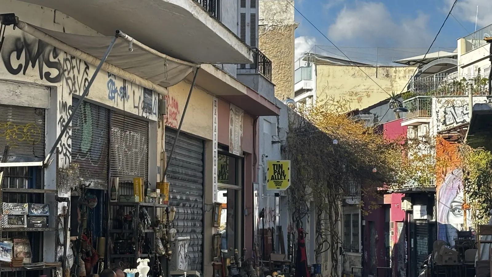 רחוב שוק פשפשים אופייני באתונה עם חנויות עתיקות וגרפיטי